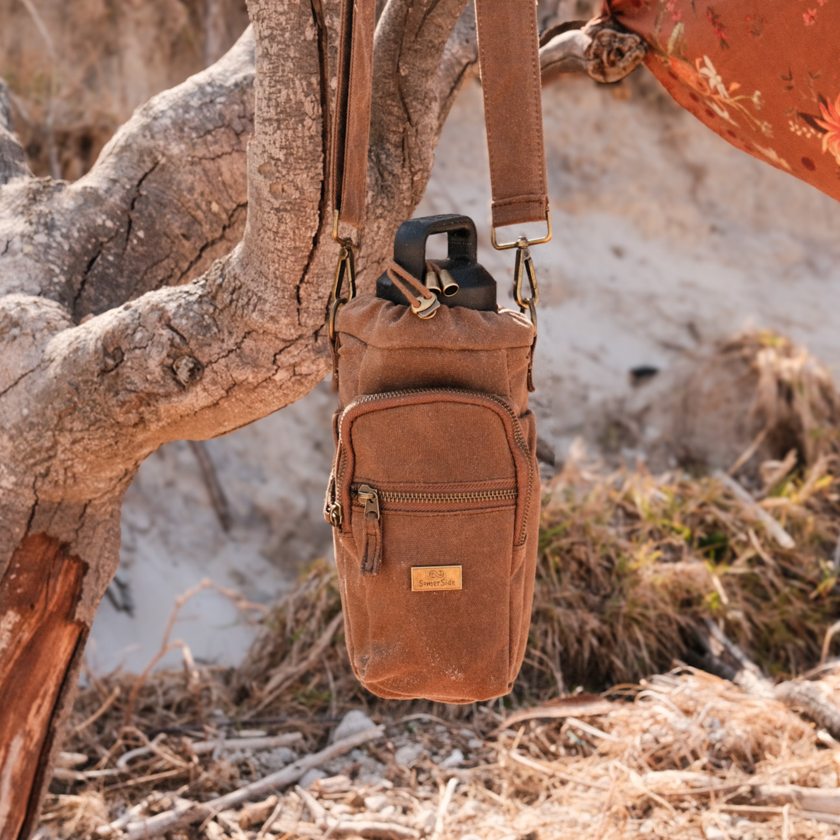 water bottle insulated bag hanging from branch at the beach