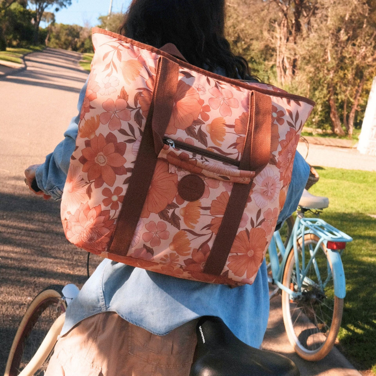 Summer Muse beach tote bag, peach retro 70s floral print, worn as a backpack on a bike