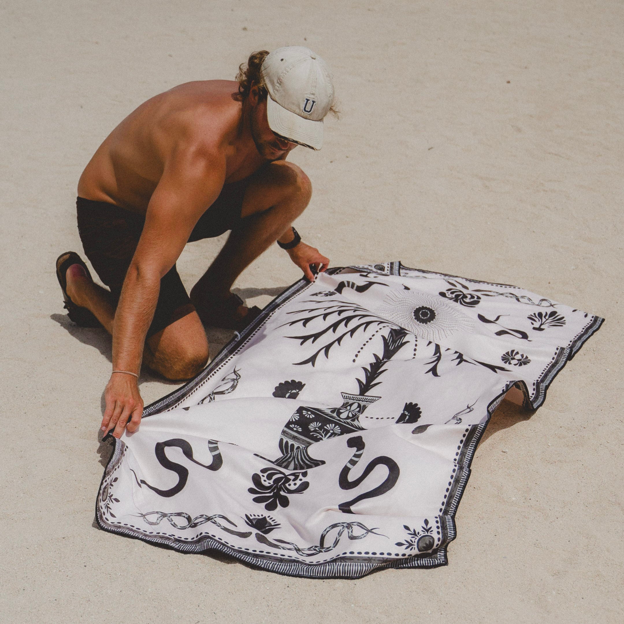 Person on a beach holding a black and white patterned towel