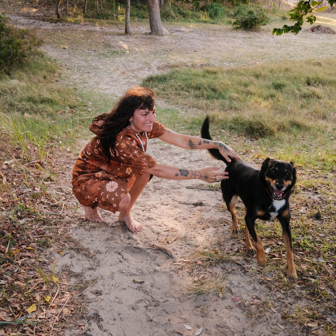 Woman playing with a dog in boho brown poncho 