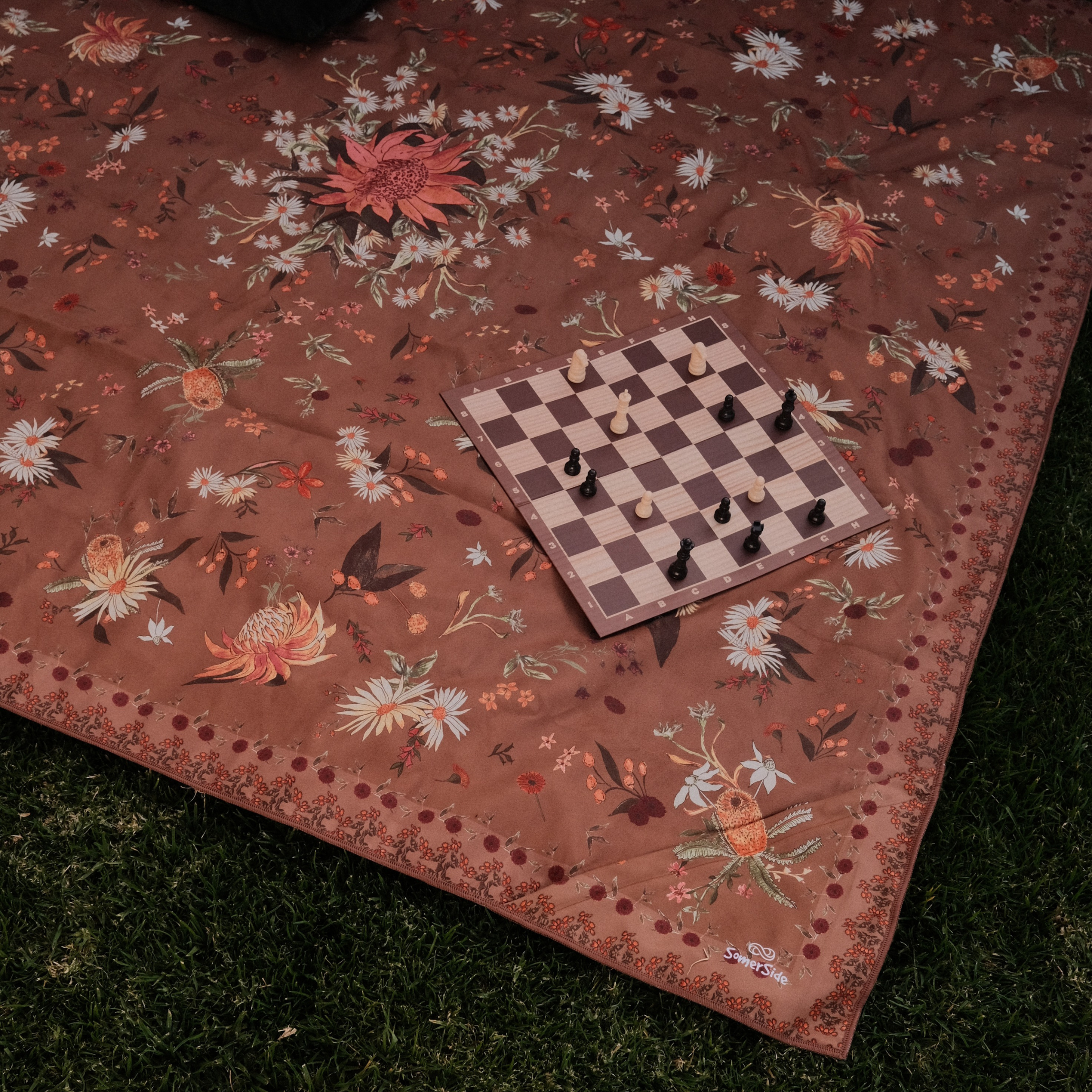 Floral-patterned towel with a chessboard and pieces 