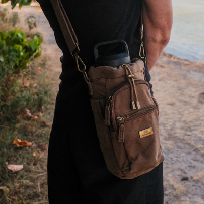 Brown shoulder bag with brass somerside logo worn by a person outdoors.