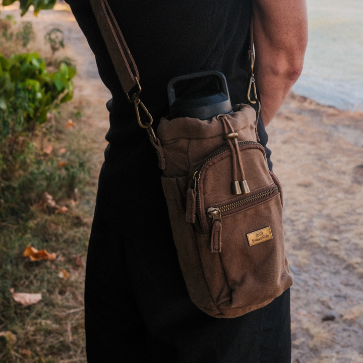Brown shoulder bag with brass somerside logo worn by a person outdoors.