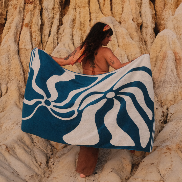 Person holding a blue and white patterned towel against a rocky cliff background