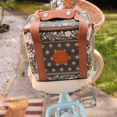 Eden mini insulated cooler bag, olive green floral bandana print, on a bike seat in the garden
