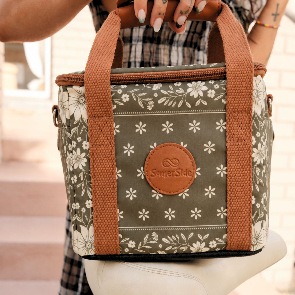 Eden mini insulated cooler bag, olive green floral bandana print, held by the handle on a bike seat