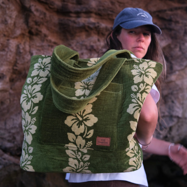 Woman holding a green tote bag with floral patterns against a rocky background