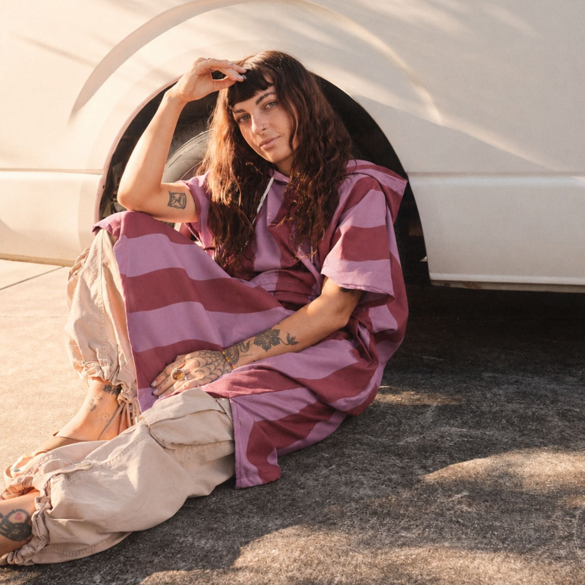 Jagger Shiraz adult hooded towel poncho, burgundy and mauve wavy stripe, sitting by a caravan wheel