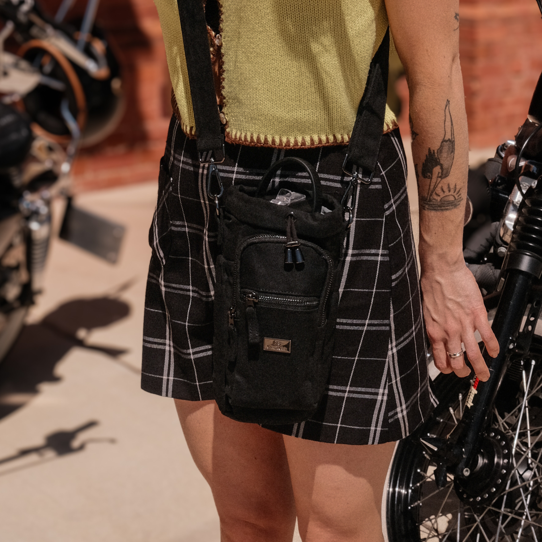 black plaid skirt with a black bottle bag made from waxed canvas
