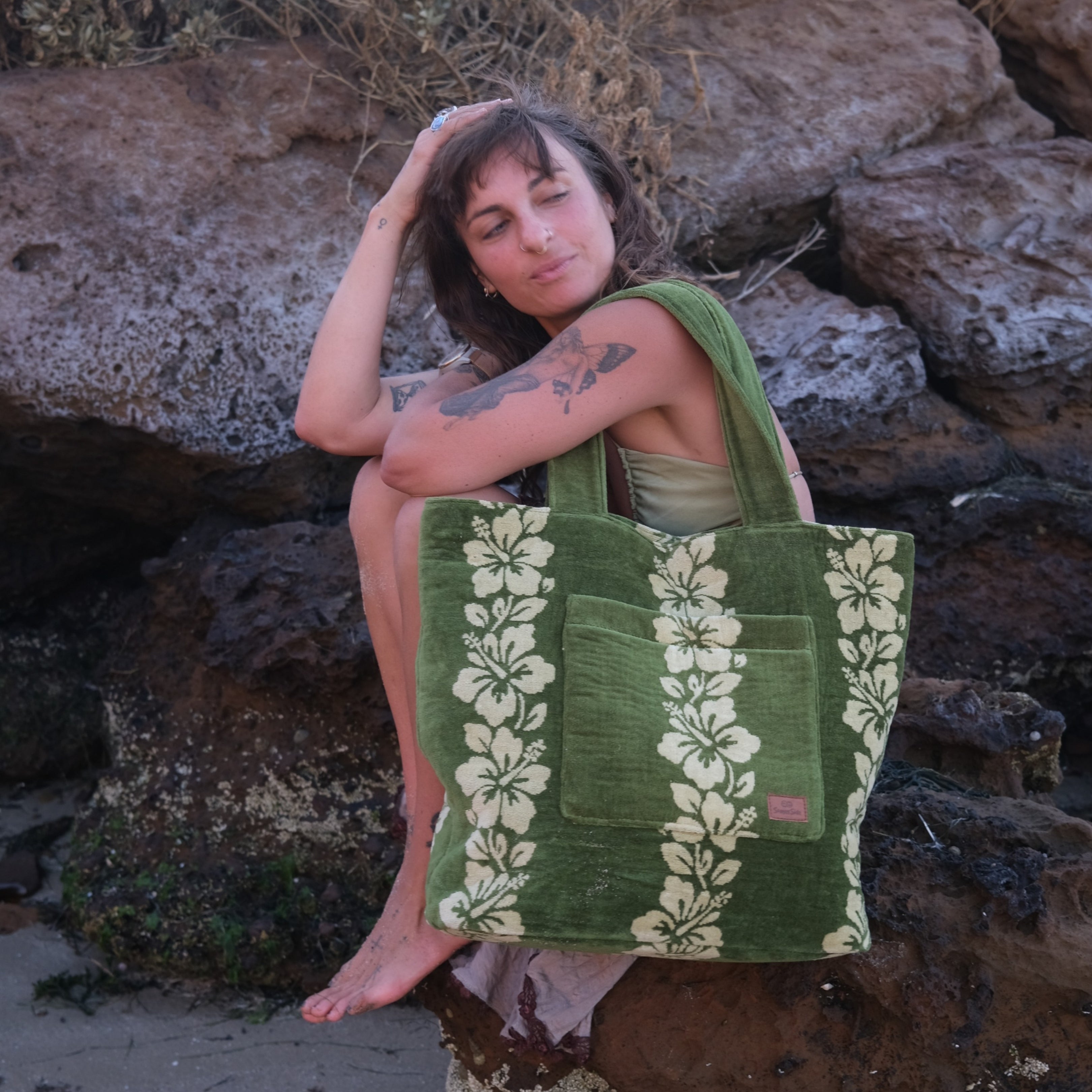 Woman holding a green tote bag with floral patterns against a rocky background