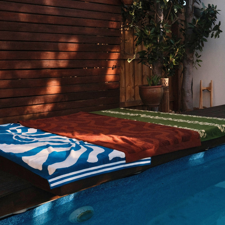 Colorful towels on a wooden deck with a pool in the foreground