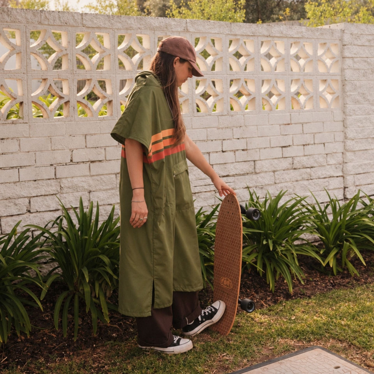 Stevie adult hooded towel poncho, olive green with retro orange stripes, with a skateboard
