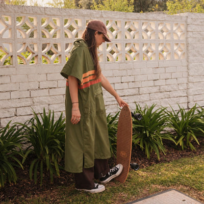 Stevie adult hooded towel poncho, olive green with retro orange stripes, with a skateboard