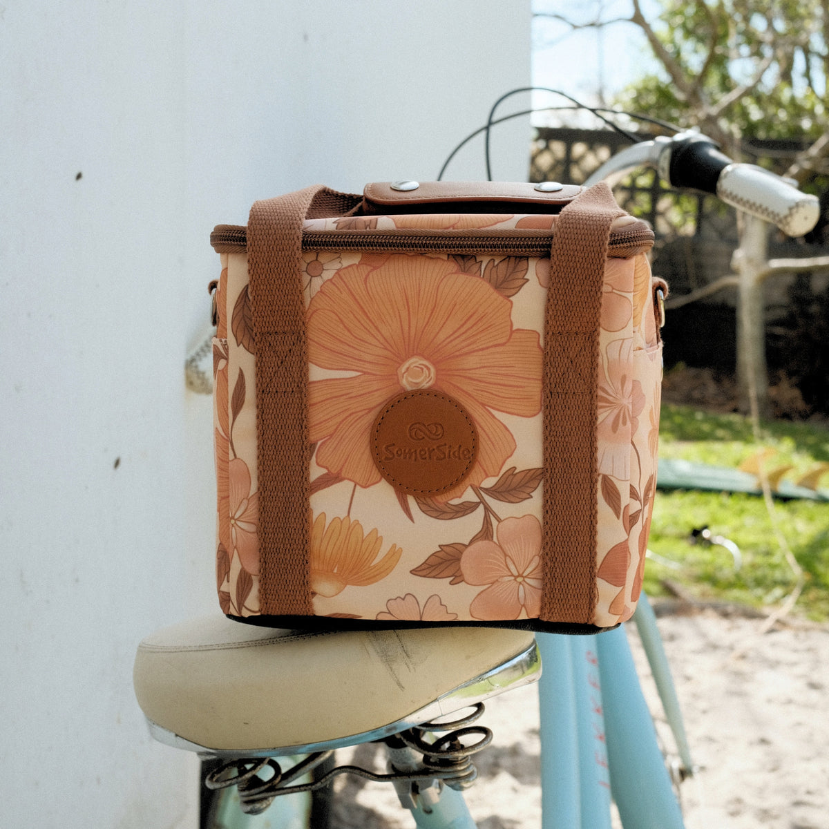 Summer Muse mini insulated cooler bag, peach retro 70s floral print, on a bike seat