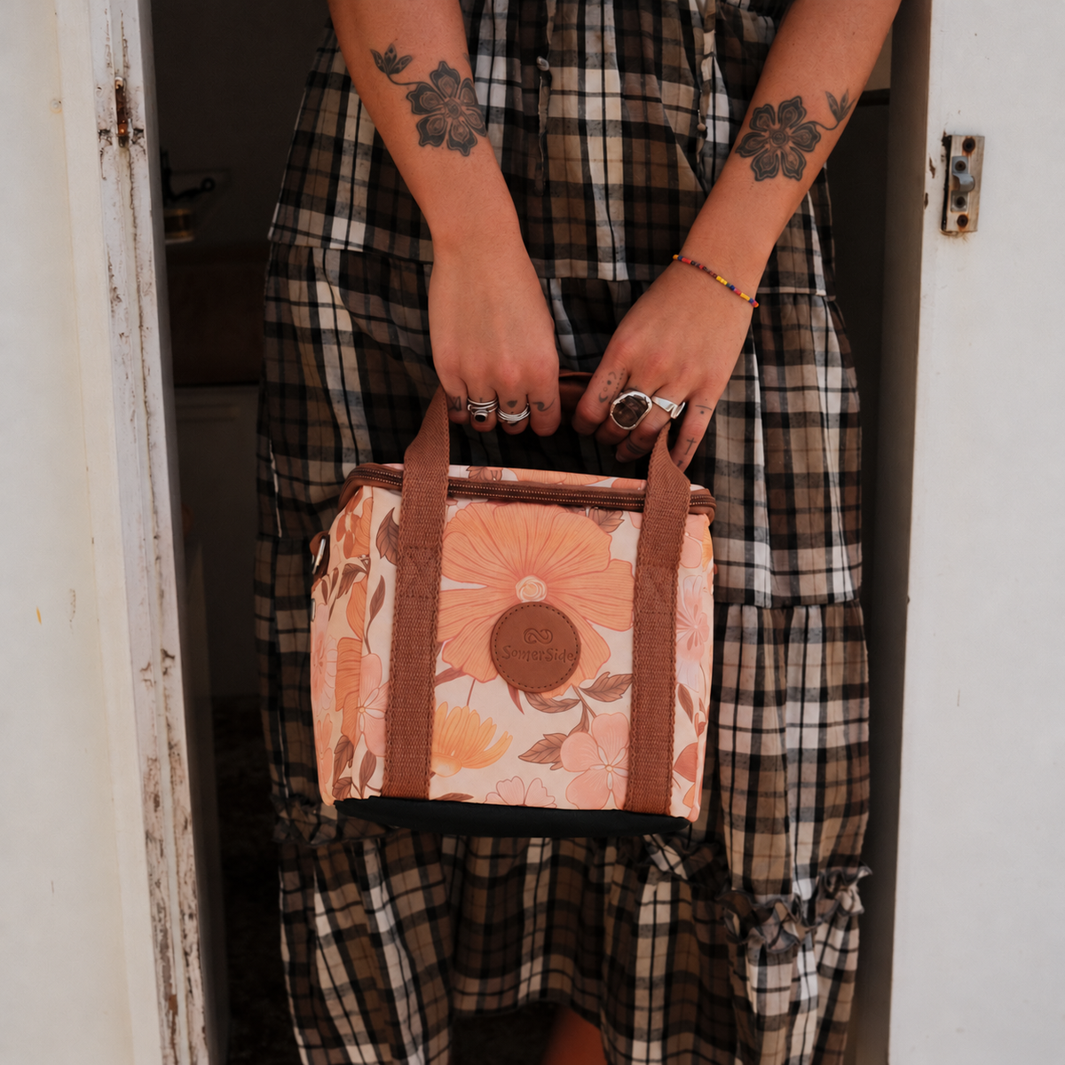 Summer Muse mini insulated cooler bag, peach retro 70s floral print, held in a caravan doorway